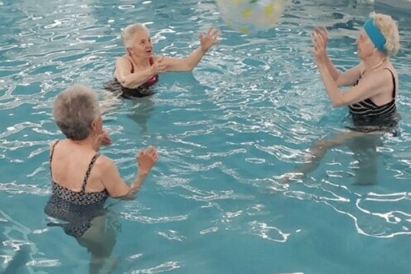 senior citizens playing with beach ball in pool