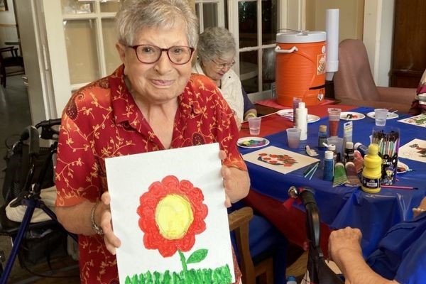 senior woman showing her painting artwork of a flower
