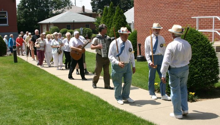 a small parade of elderly people following a small band