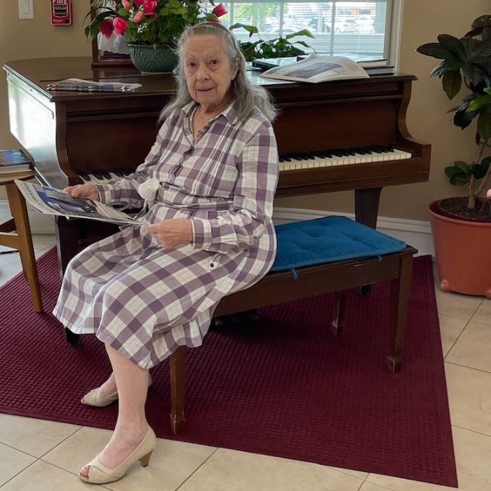 older woman sitting by piano