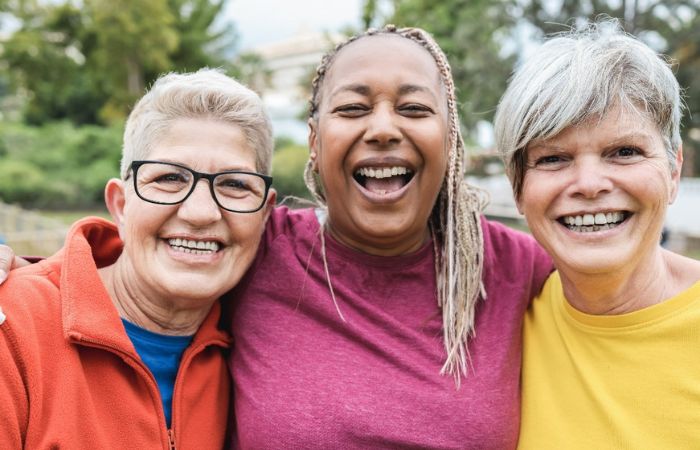3 senior women smiling standing arm in arm