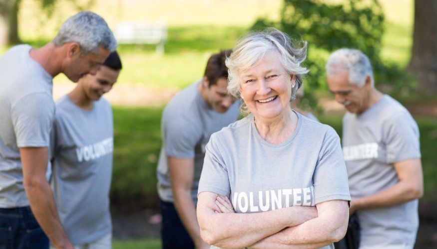 senior woman smiling arms folded wearing a tshirt that says volunteer on it