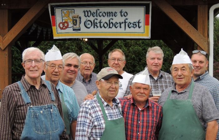 men standing together for a photo under a sign that reads Oktoberfest
