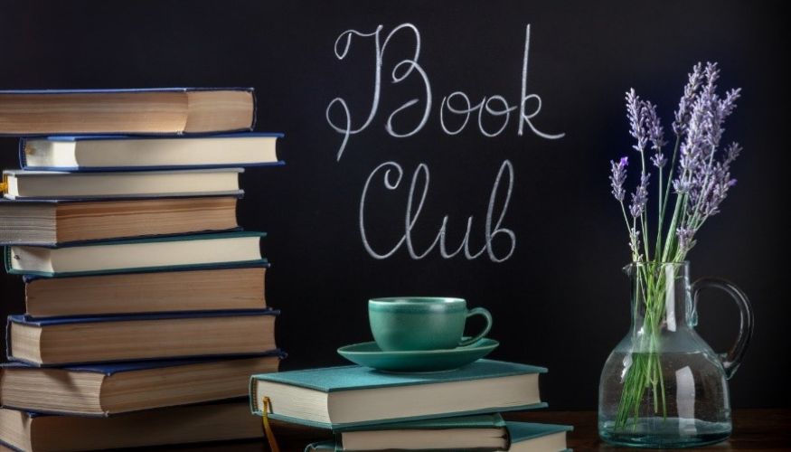 books on a desk with a flower in a vase and "book club" written