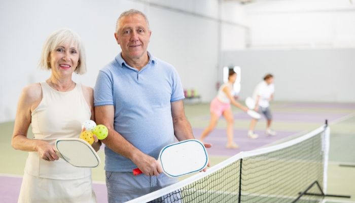 a couple standing side by side on a pickleball court