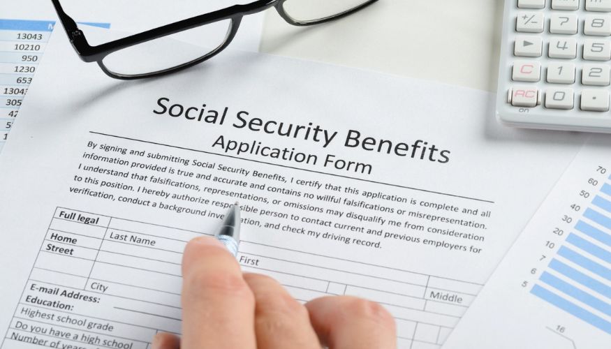 social security benfits application form with a hand holidng a pen filling it out