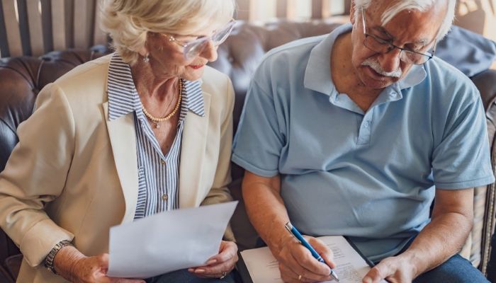 a senior couple sitting together going over a checklist on a clipboard