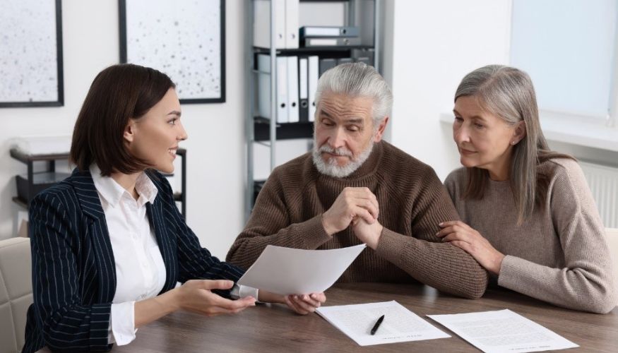 a woman going over some paperwork with a an older couple sitting at a table