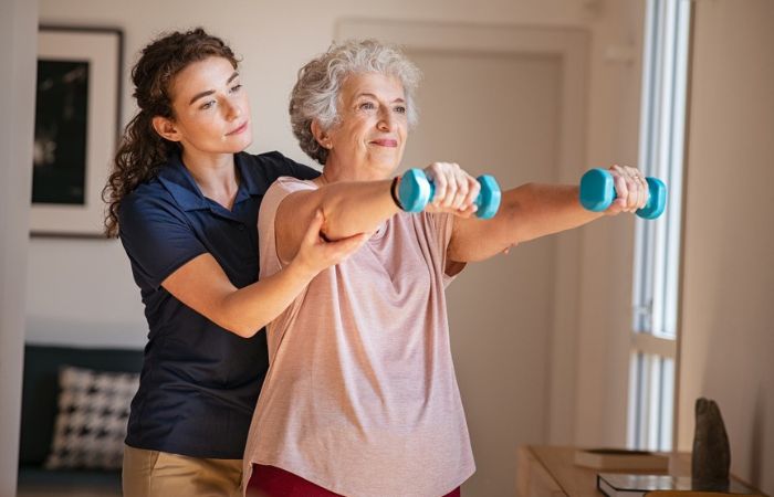 Female PT working with an older woman using dumbbells