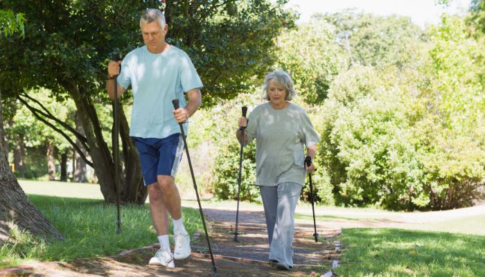 A senior couple walking in a park using walking poles